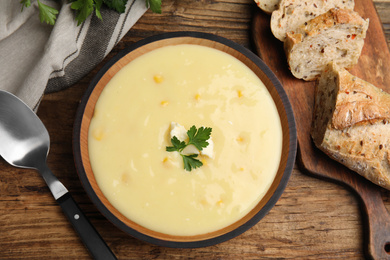 Photo of Delicious corn cream soup served on wooden table, flat lay