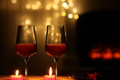 Photo of Glasses of wine and candles against blurred lights, space for text. Romantic dinner