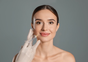 Photo of Beautiful woman getting facial injection on grey background. Cosmetic surgery