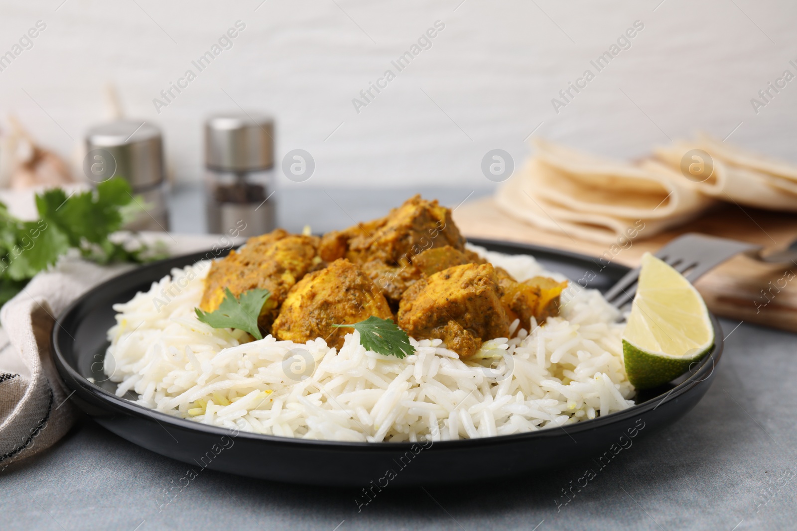 Photo of Delicious chicken curry with rice on grey table, closeup