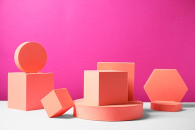 Geometric figures on white table against bright pink background. Stylish presentation for product