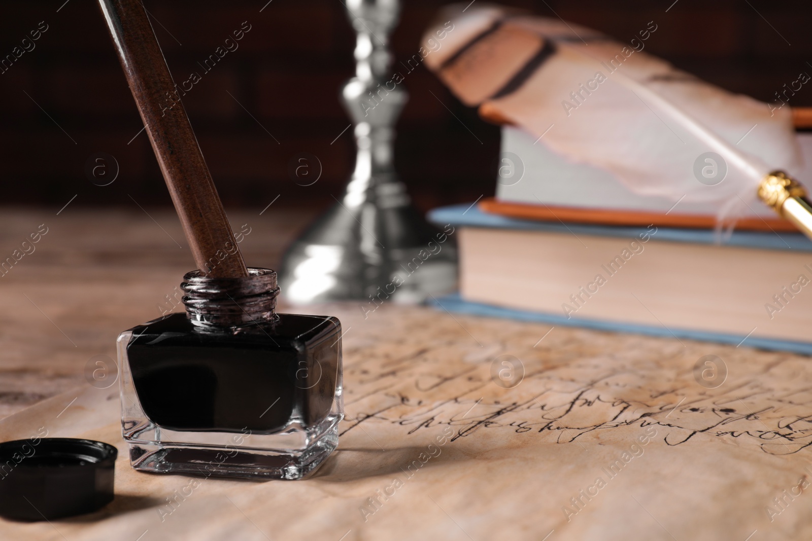 Photo of Inkwell with fountain pen on vintage parchment with text, closeup