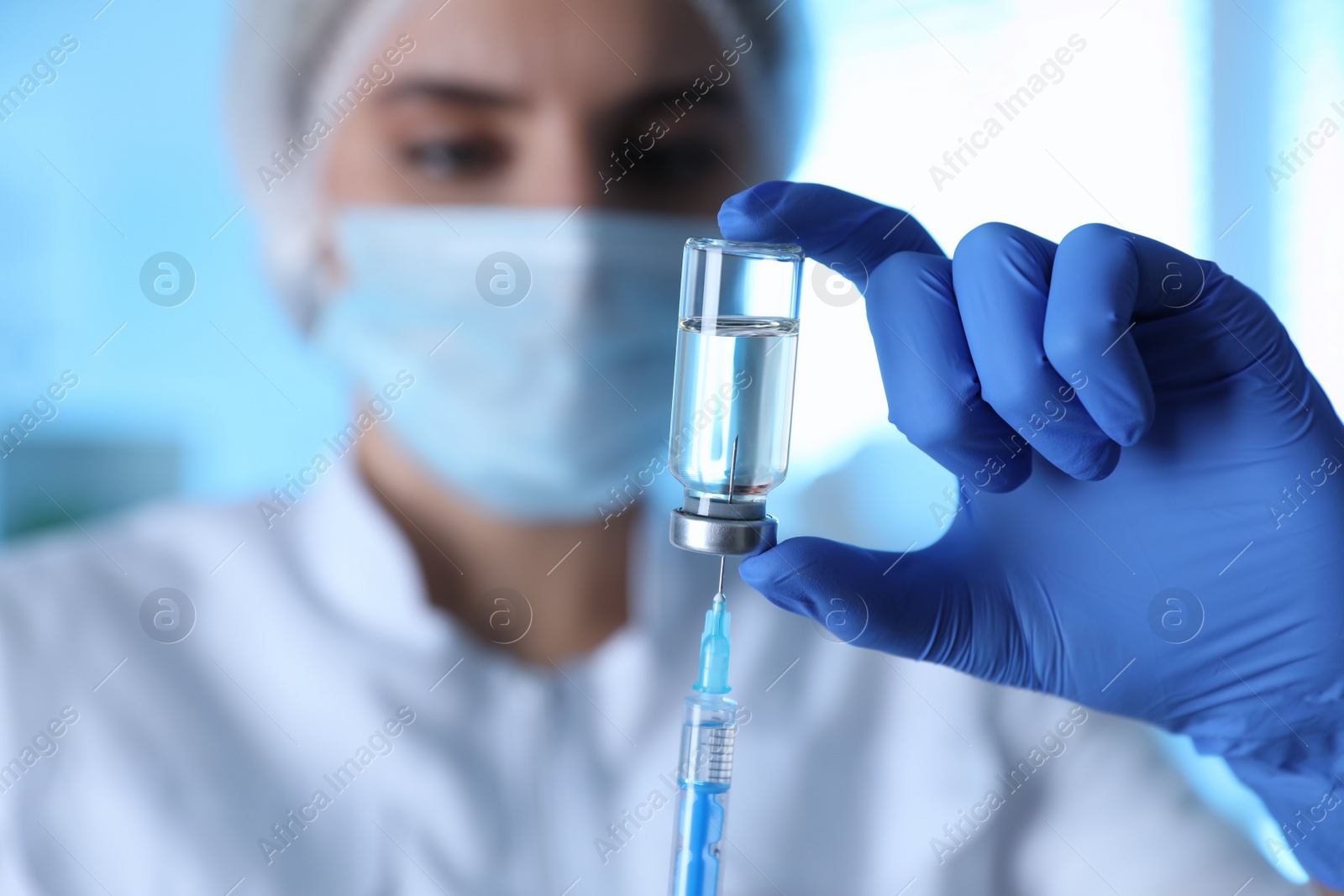 Photo of Doctor filling syringe with medication in clinic, focus on hand. Vaccination and immunization