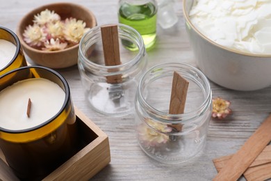 Photo of Glass jars with wooden wicks on light table. Making homemade candles