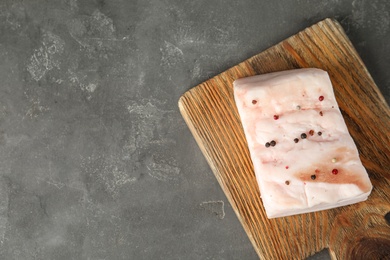 Photo of Board with pork fatback on grey stone background, top view. Space for text