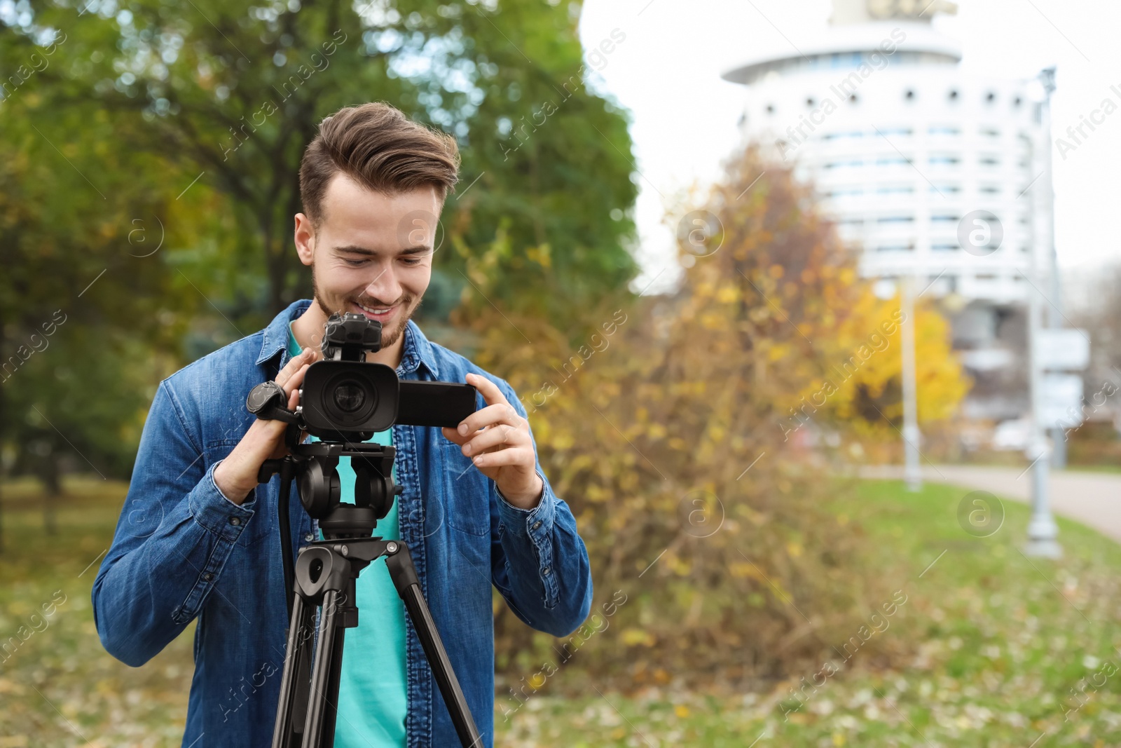 Photo of Video operator with camera working in park. Space for text