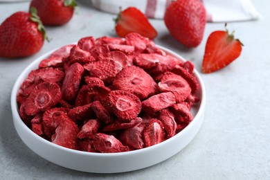 Photo of Freeze dried and fresh strawberries on light grey table, closeup