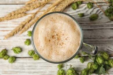 Flat lay composition with tasty beer, wheat spikes and fresh green hops on wooden background