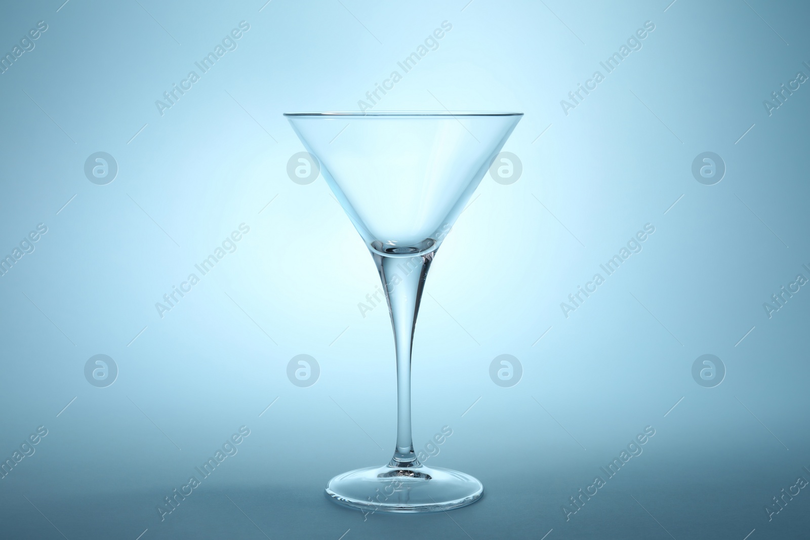 Photo of Elegant empty martini glass on light blue background