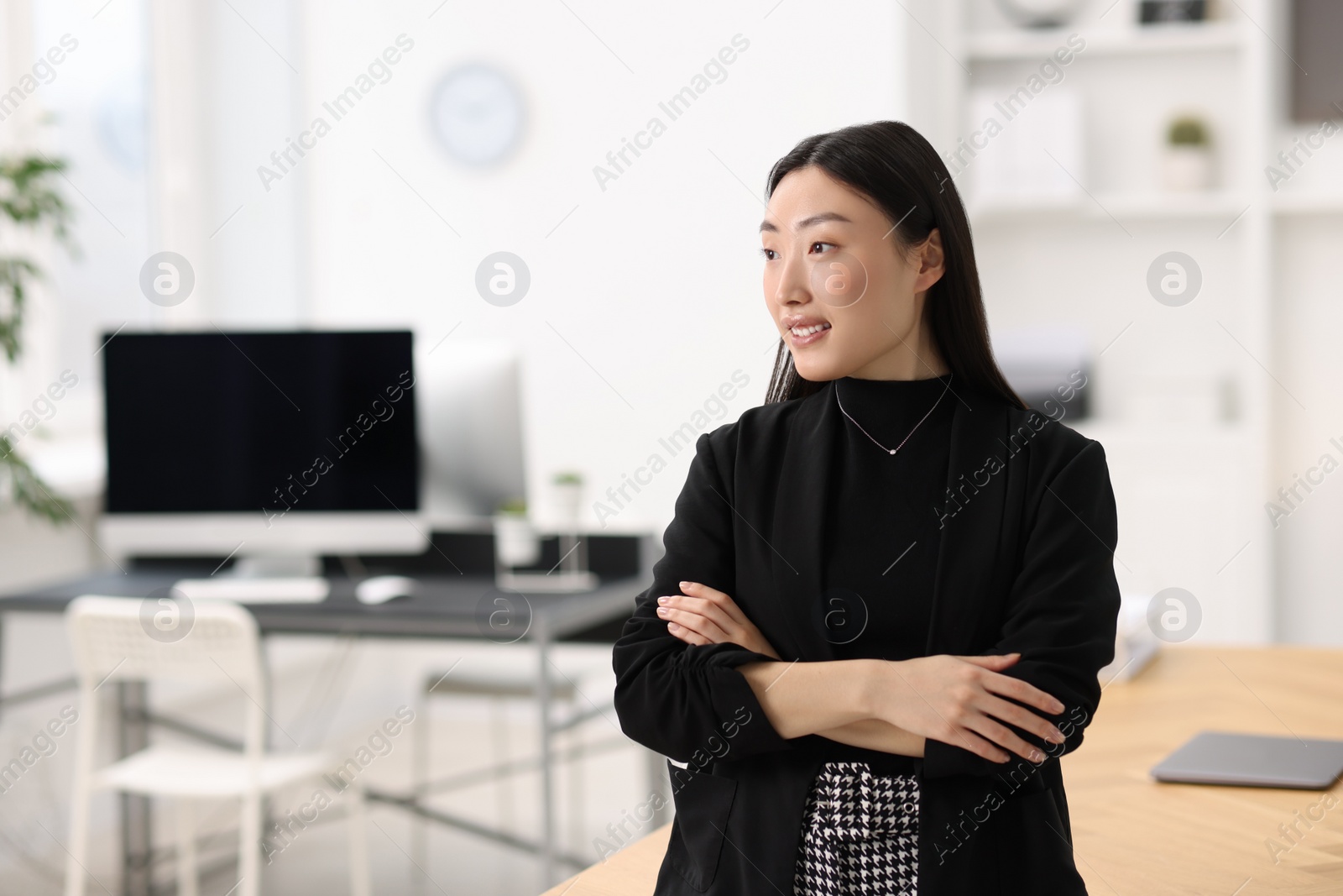 Photo of Portrait of smiling businesswoman with crossed arms in office. Space for text