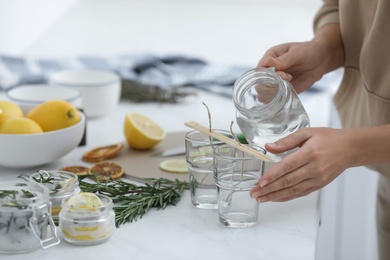 Woman making natural mosquito repellent candles at white table, closeup