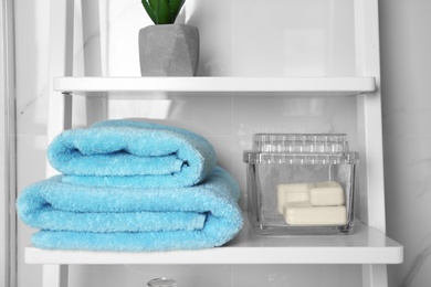 Photo of Fresh towels and soap bars on white shelf in bathroom