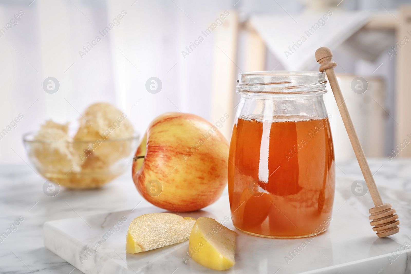 Photo of Jar of honey, apples and dipper on marble table