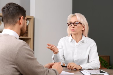 Photo of Boss and employee discussing work issues at wooden table in office