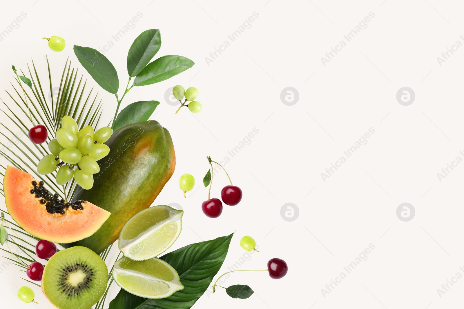 Image of Tropical layout with fresh exotic fruits and green leaves on light background, top view