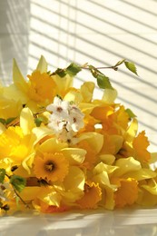 Photo of Yellow daffodils and beautiful white flowers of plum tree on windowsill, closeup