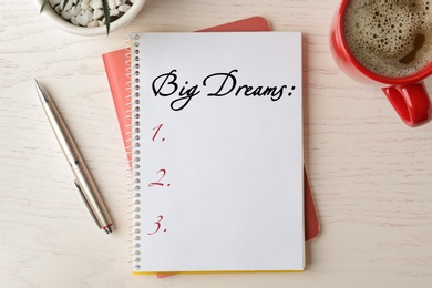 Image of Notebook with dreams list on wooden table, flat lay 