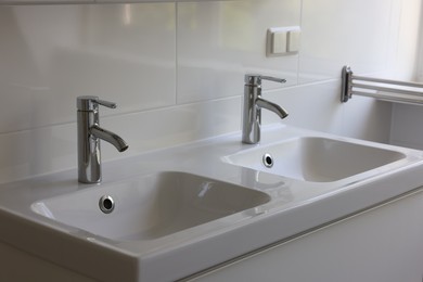 Photo of White clean sinks with water taps in bathroom