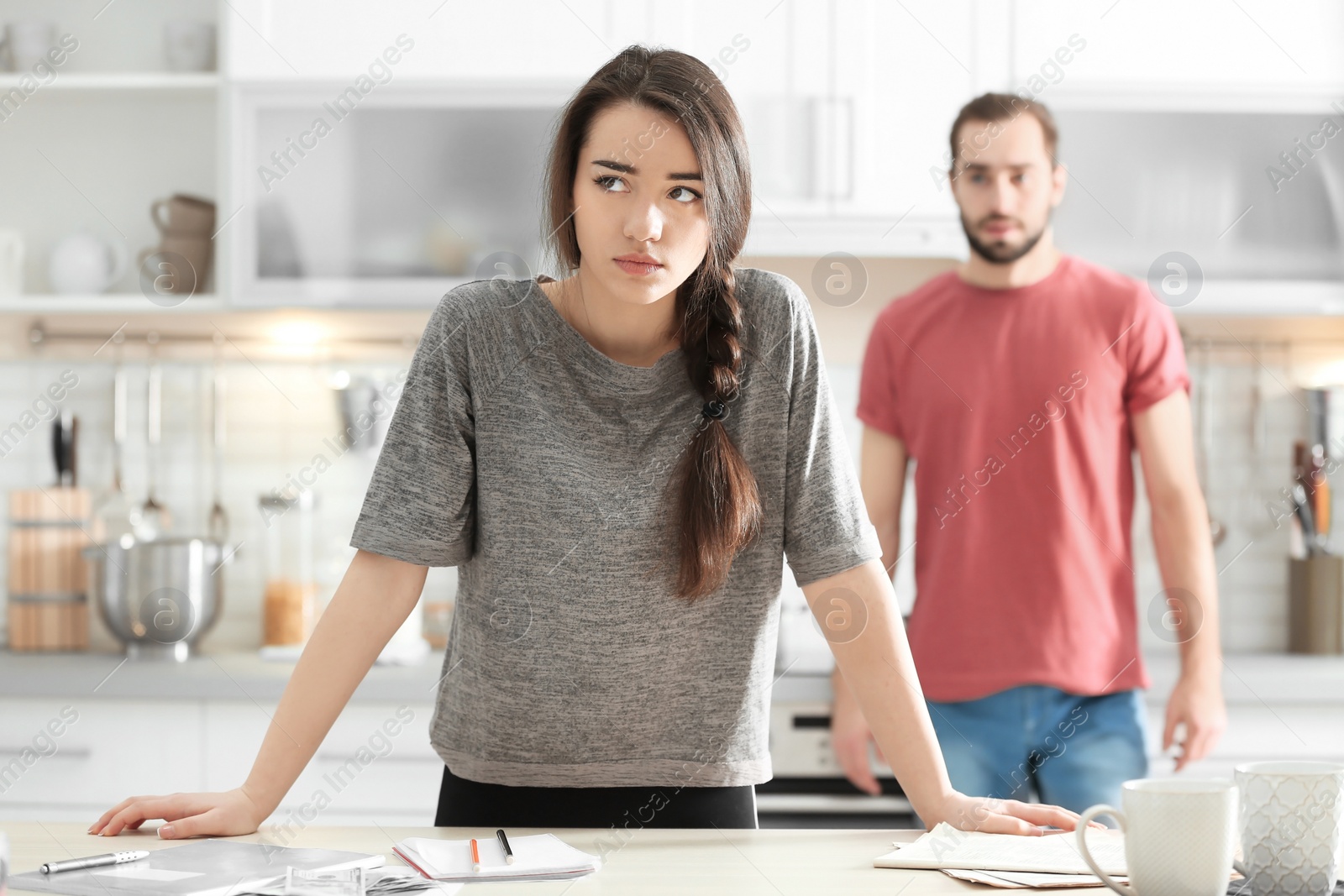 Photo of Young couple ignoring each other after having argument in kitchen