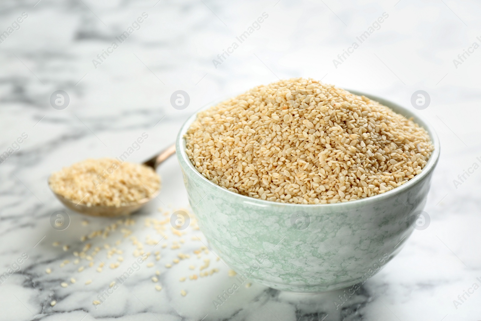 Photo of Sesame seeds in bowl on white marble table