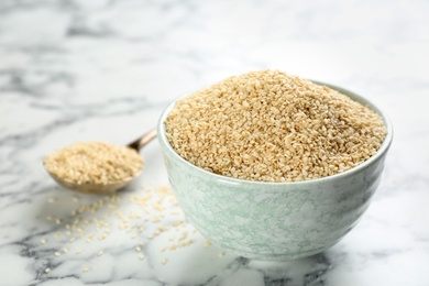 Photo of Sesame seeds in bowl on white marble table