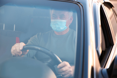 Photo of Senior man with medical mask in car. Virus protection