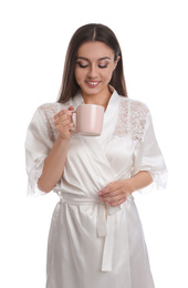 Young woman in silk robe with cup of beverage on white background