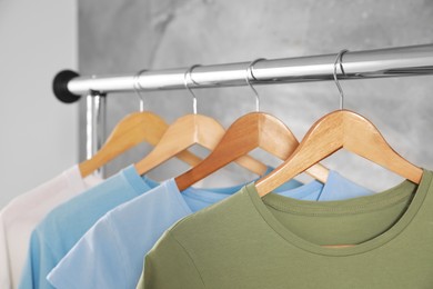 Photo of Clean T-shirts hanging on rack indoors, closeup