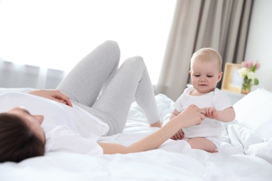 Photo of Happy mother with little baby on bed at home