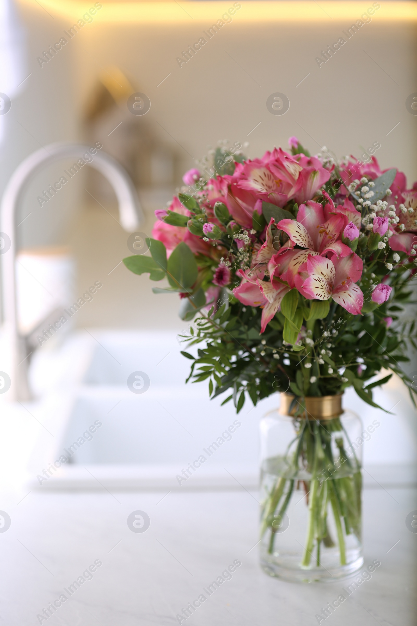 Photo of Vase with beautiful alstroemeria flowers on countertop in kitchen. Interior design