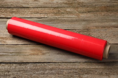 Photo of Roll of red plastic stretch wrap on wooden background