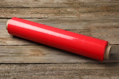 Roll of red plastic stretch wrap on wooden background