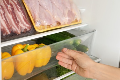 Photo of Woman opening refrigerator drawer with fresh vegetables, closeup