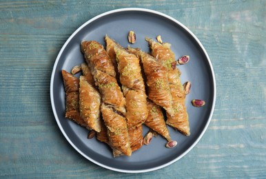 Photo of Delicious baklava with pistachio nuts on light blue wooden table, top view