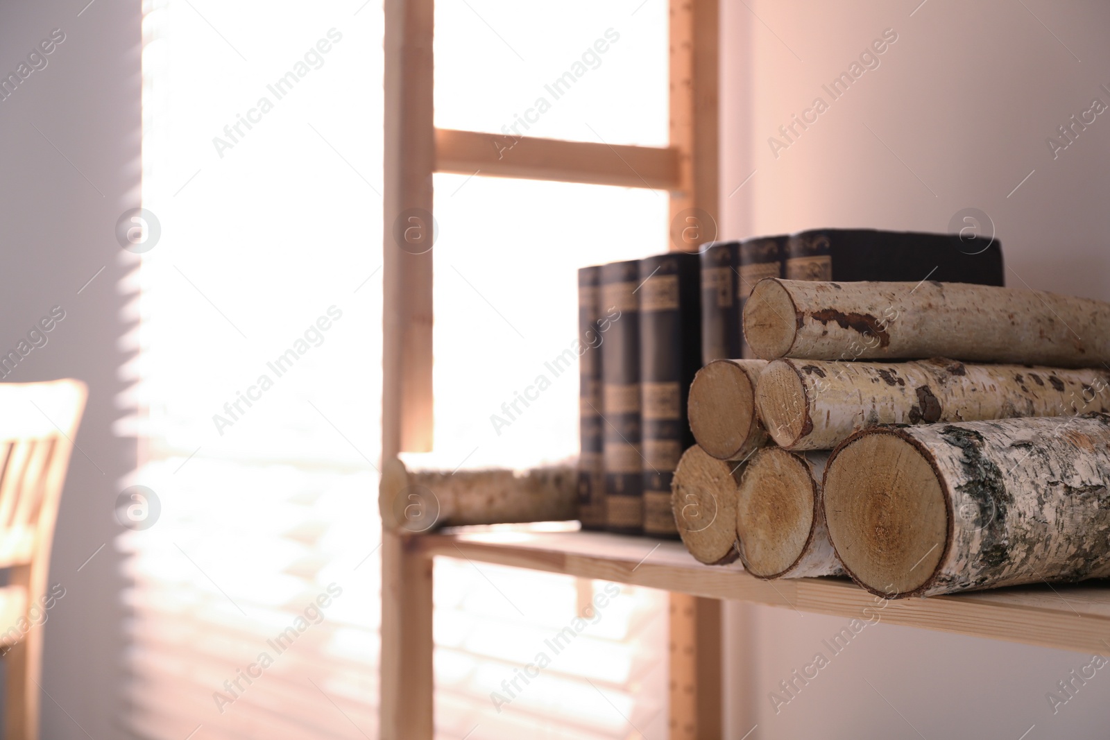 Photo of Shelving unit with stacked firewood and books near wall. Idea for interior design