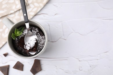 Photo of Tasty chocolate mug pie, mint and spoon on white textured table, flat lay with space for text. Microwave cake recipe