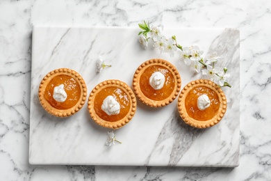 Tasty tartlets with jam on light background, top view