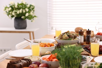 Healthy vegetarian food and glasses of juice on table indoors