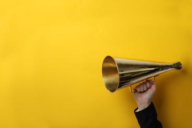 Woman holding retro megaphone on color background