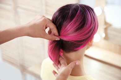 Photo of Professional hairdresser working with young woman in beauty salon. Trendy hair color