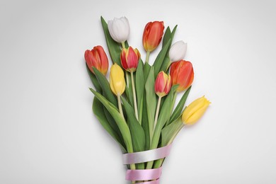 Photo of Bouquet of beautiful colorful tulip flowers tied with pink ribbon on white background, top view