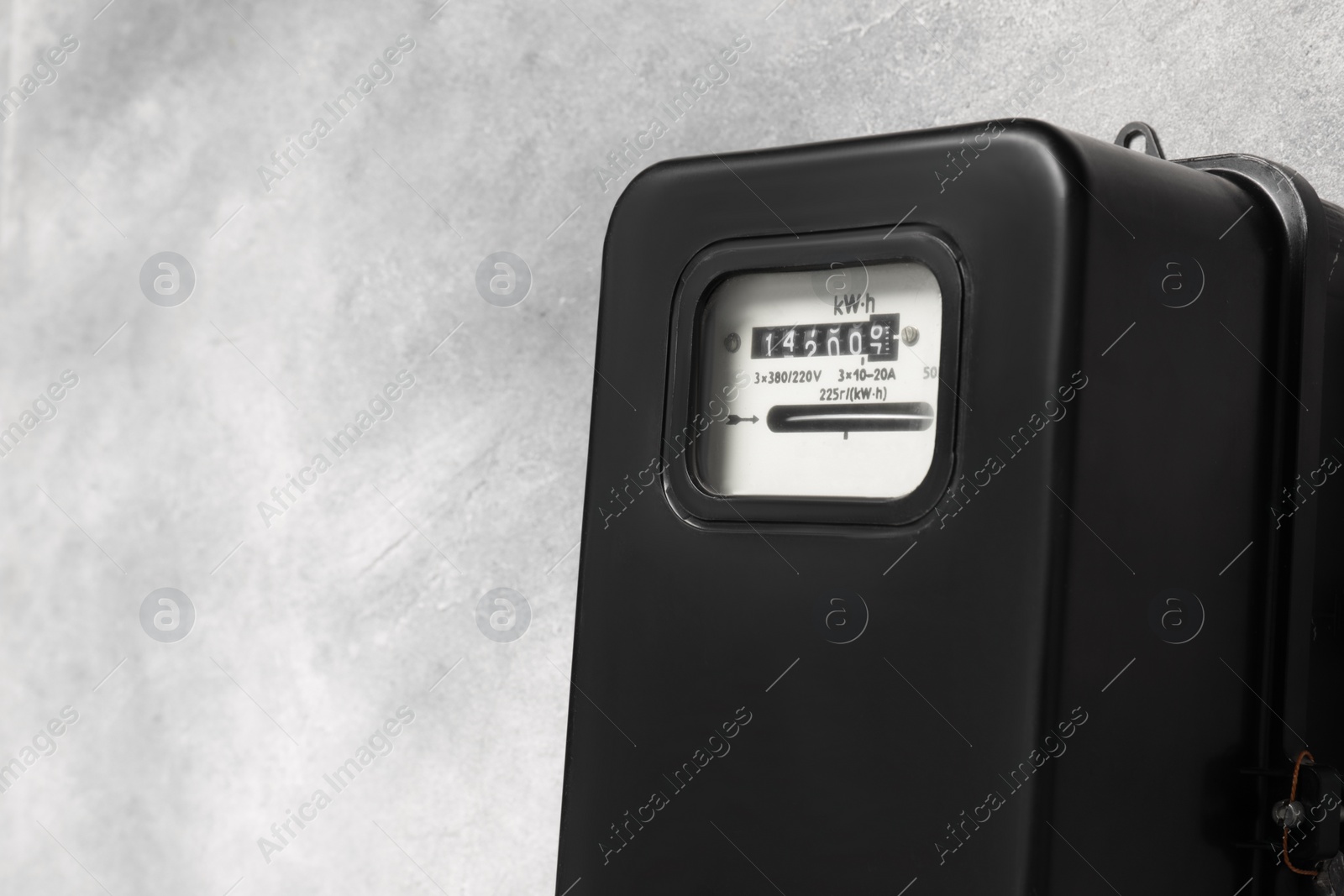 Photo of Electricity meter on light grey wall, closeup and space for text