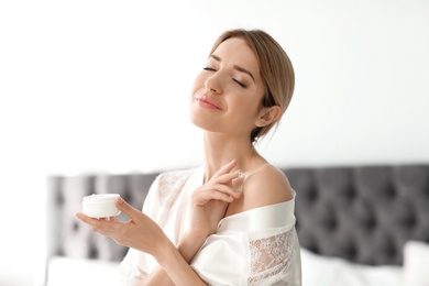 Young woman with jar of body cream at home