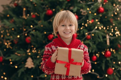 Photo of Little child with gift box near Christmas at home
