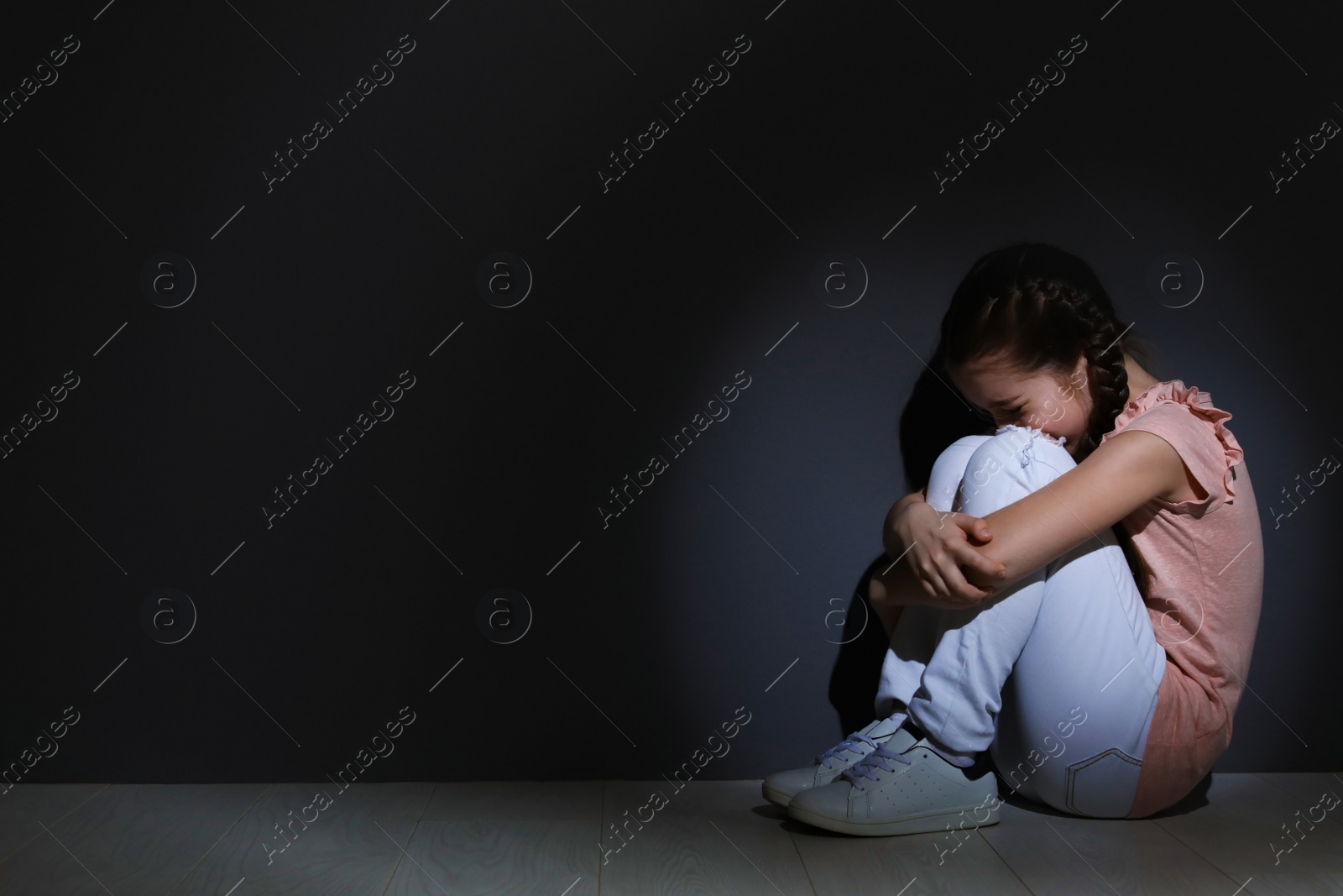 Photo of Depressed little girl sitting on floor indoors. Time to visit child psychologist