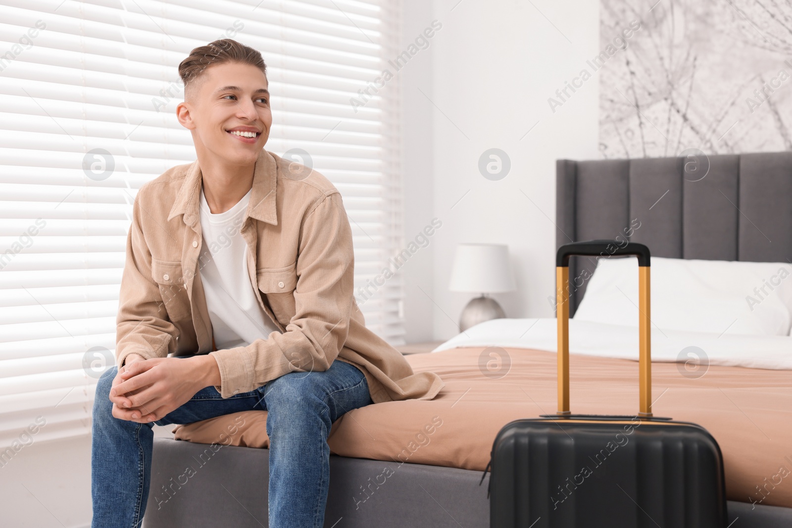 Photo of Smiling guest relaxing on bed in stylish hotel room