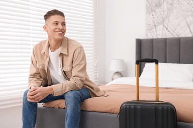 Photo of Smiling guest relaxing on bed in stylish hotel room