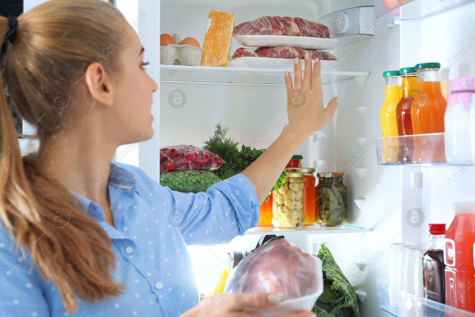 Photo of Woman taking fresh meat out of refrigerator in kitchen