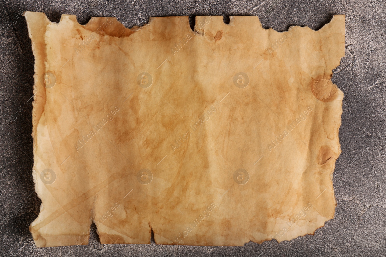 Photo of Sheet of old parchment paper on gray textured table, top view