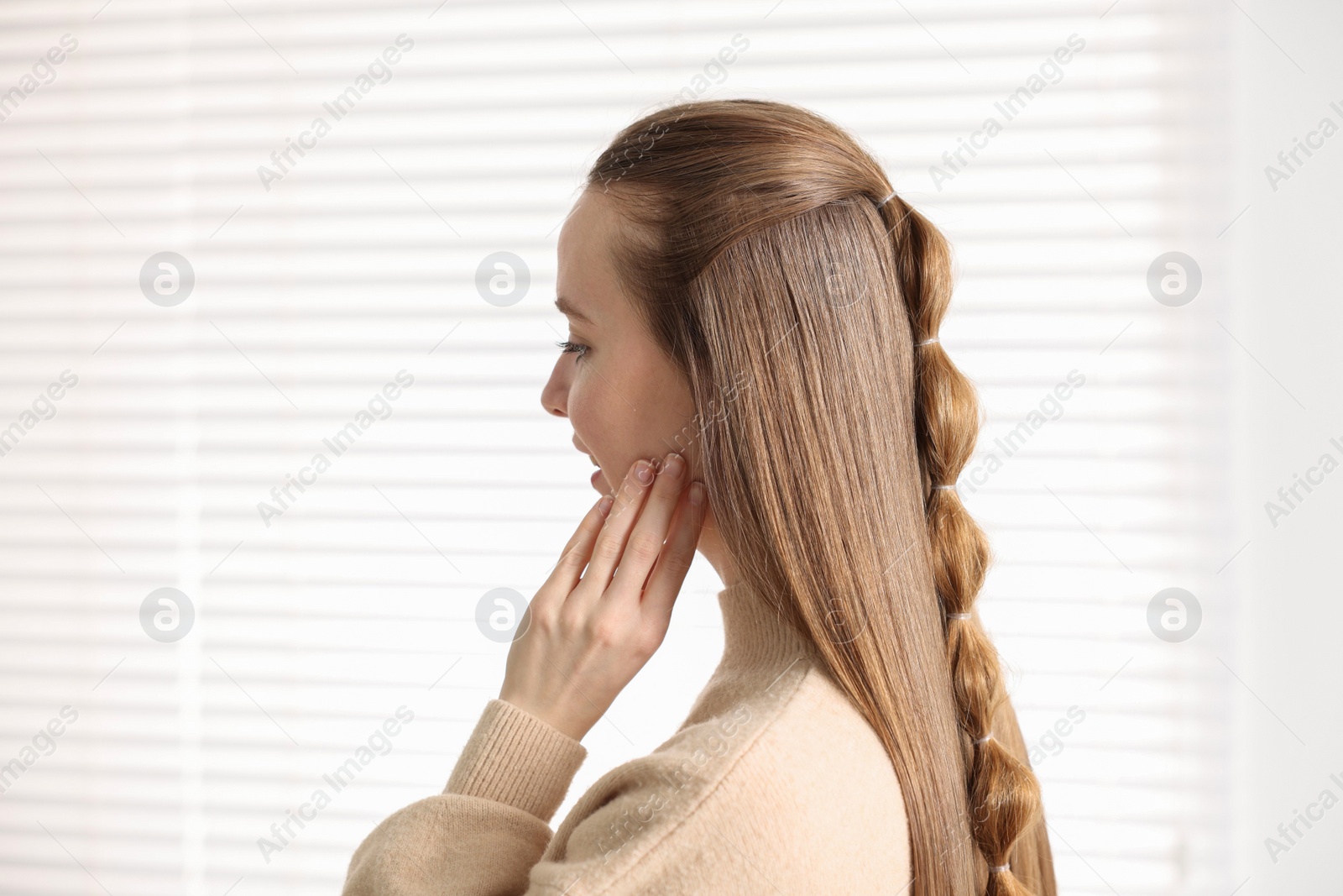 Photo of Young woman with long braided hair indoors